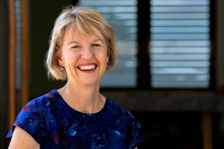 Headshot of female social worker sitting in sunshine smiling at camera for personal branding and wellness branding photos