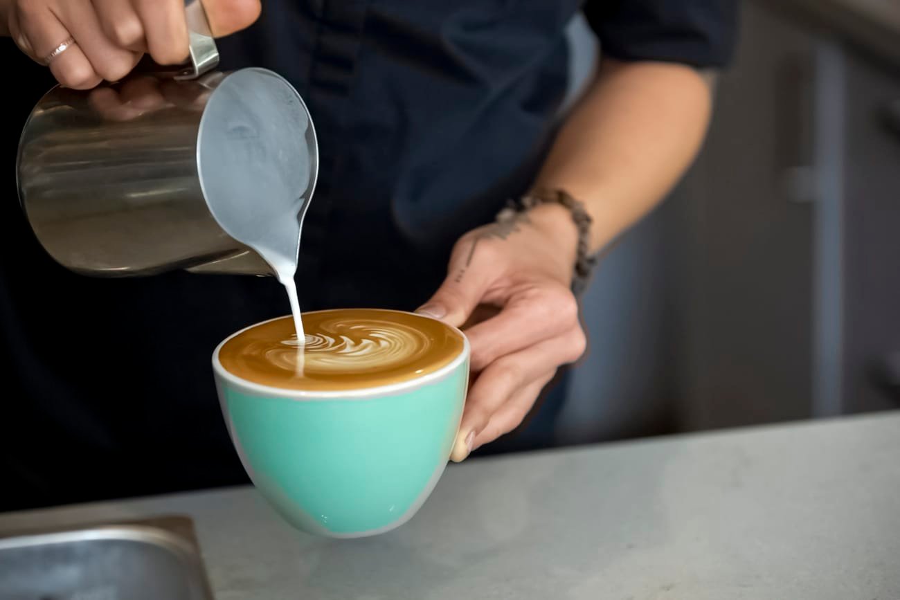 Pouring milk into coffee cup for marketing purposes