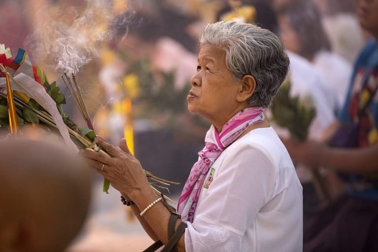 Woman praying with incense at temple for wellness branding