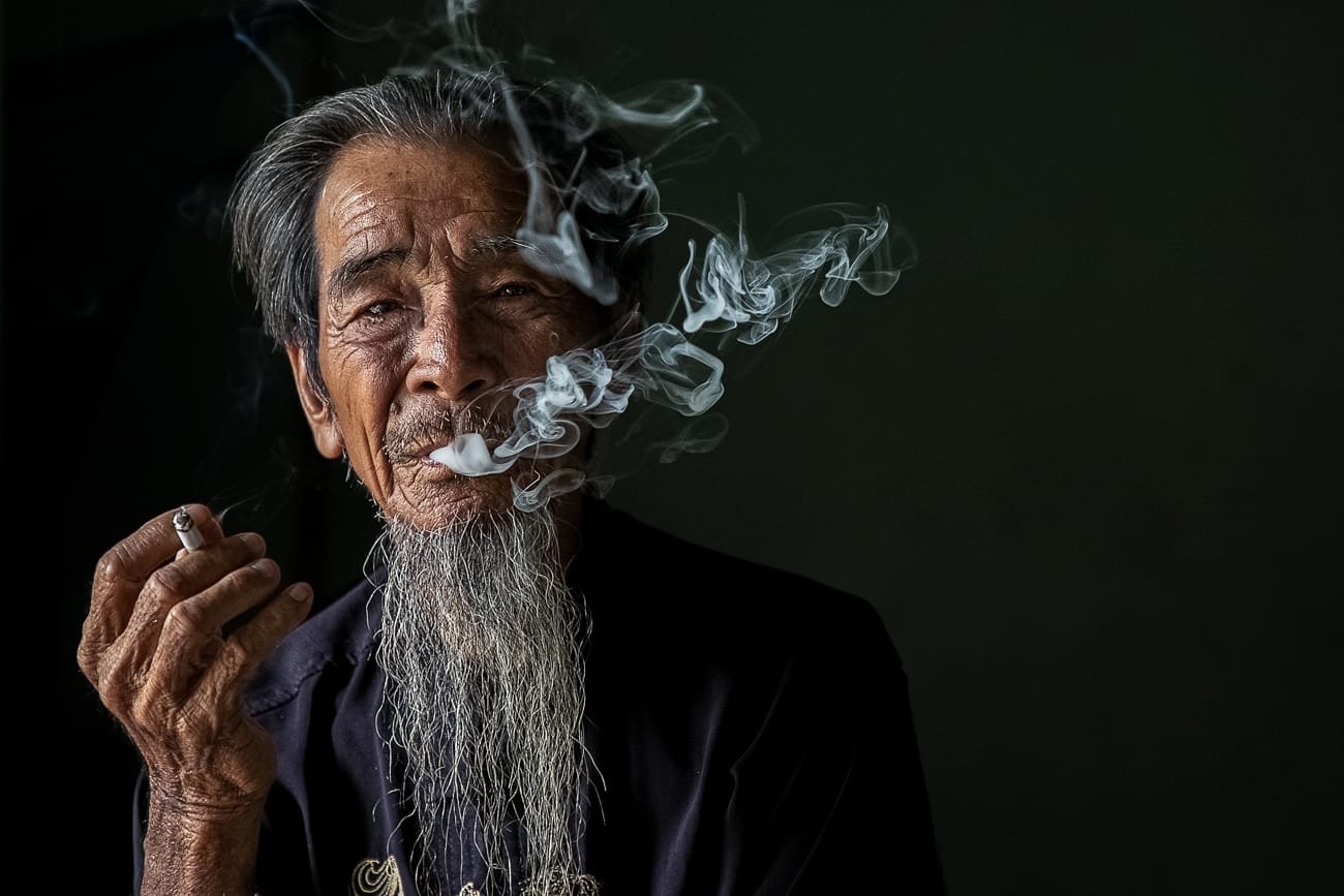 Male portrait blowing smoke in darkened room