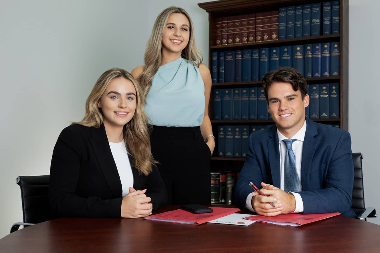 Corporate branding photo of 3 legal staff in office with bookcase in background