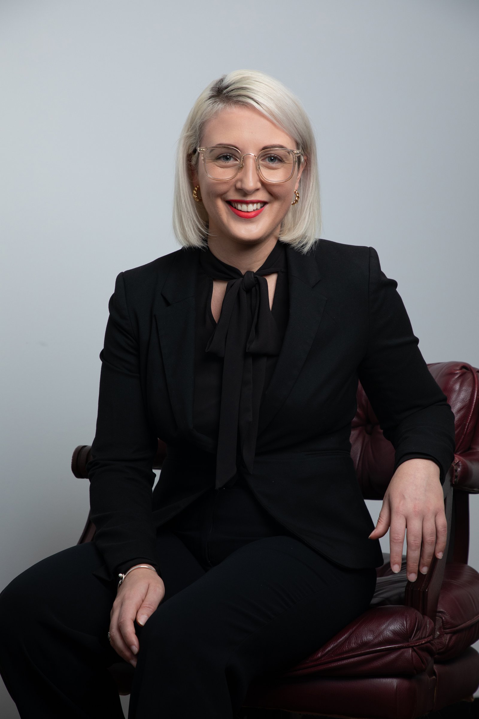 Formal corporate branding headshot of female solicitor in front of white wall