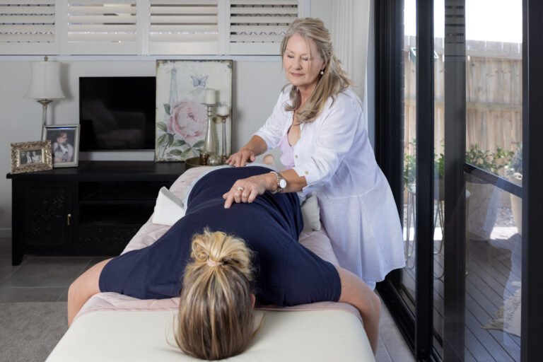 Spinal flow practitioner working on client on bed with hands placed along spine for wellness branding photo