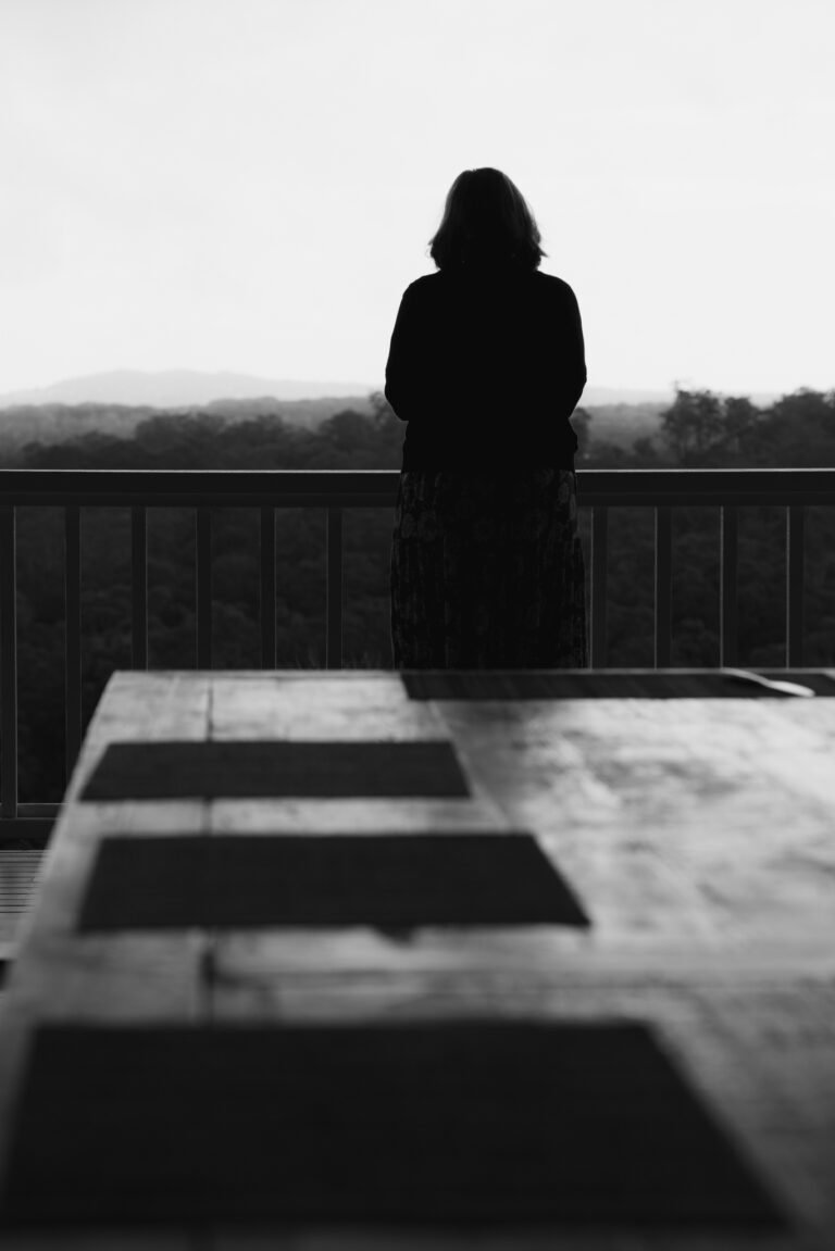 Black and white photo of silhouetted woman staring over balcony for wellness branding