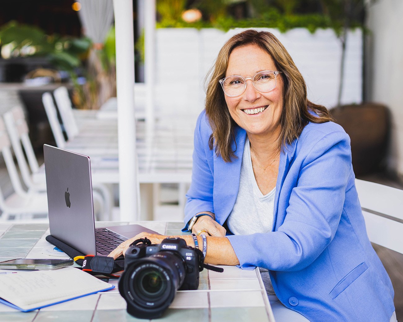 Smiling female photographer seated at table with laptop camera