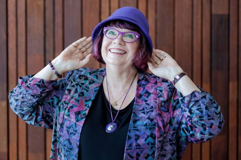 Personal branding photo of communication coach joyfully with hands holding hat on head and looking upwards for wellness branding photos