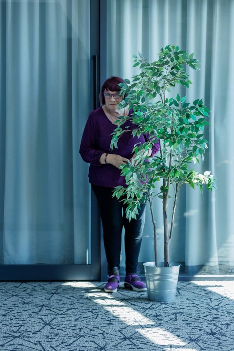 Communications Coach and Author hiding behind pot plant for wellness branding photo