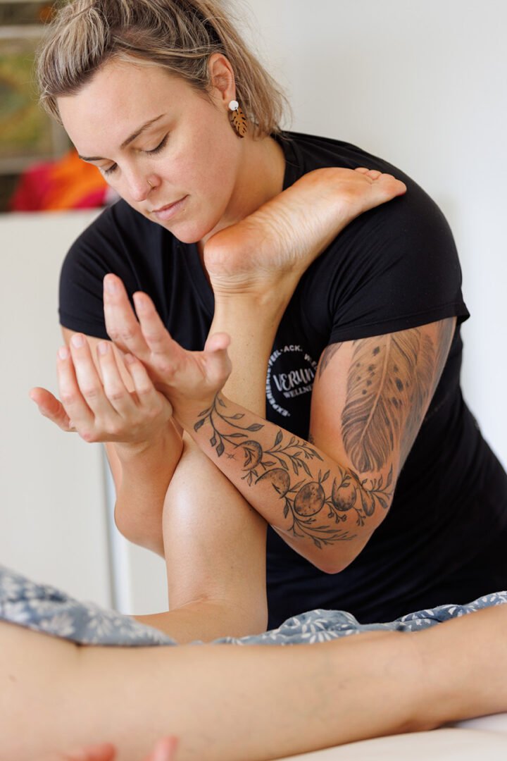 Wellness branding photo of female Kahuna massage therapist tenderly holding leg and massaging calf