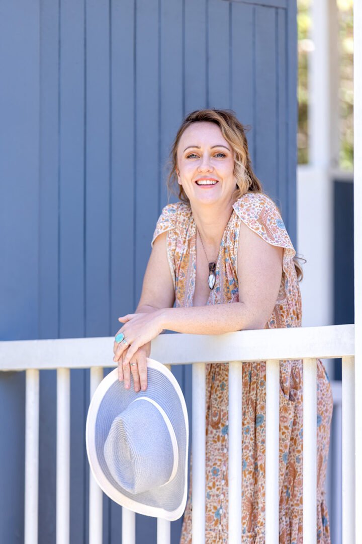Wellness Branding photo for relationship coach of lady holding sunhat and leaning over railing