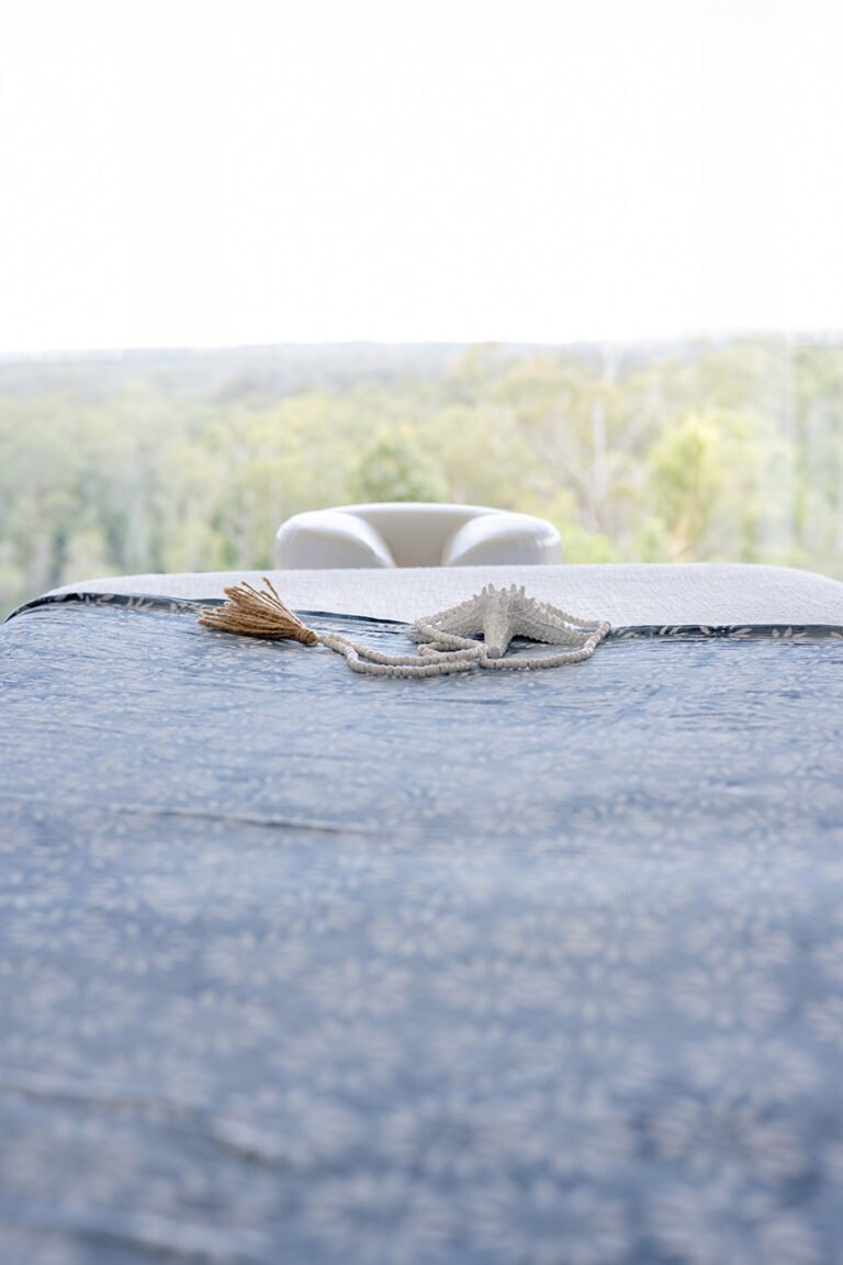 Close up of massage table with cloth and shell with a view out to trees for wellness and business branding photos