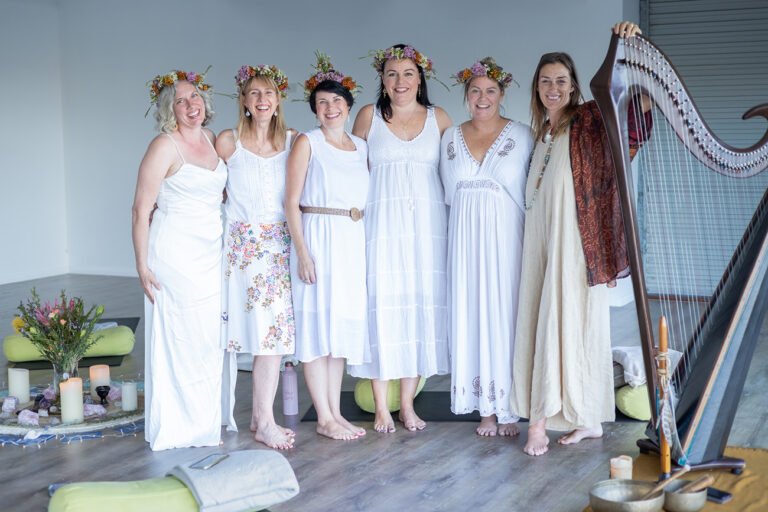 Group photo of women's retreat participants dressed in white and wearing floral crowns for wellness branding photos